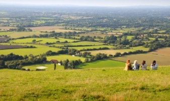 Four people sitting on hillside with South Downs National in background